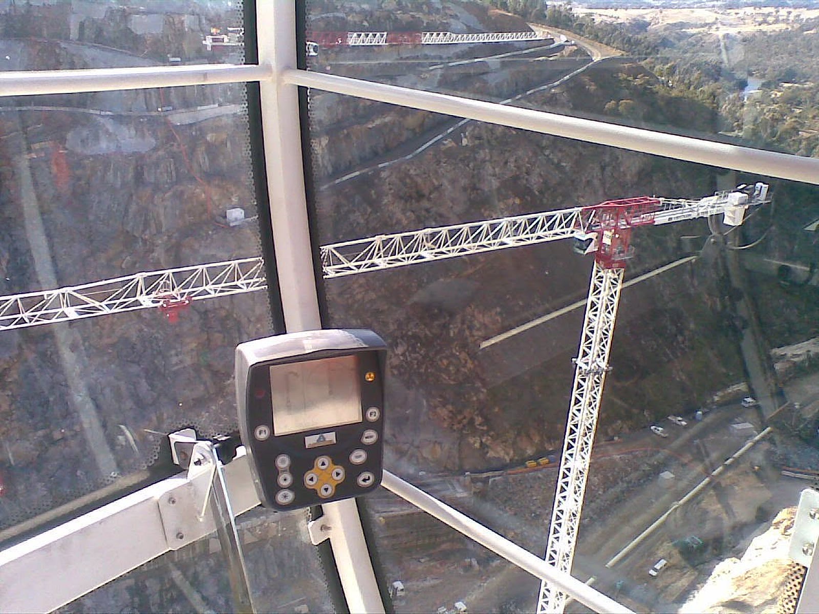 Tower crane cab interior with controls, looking out over two crane jibs